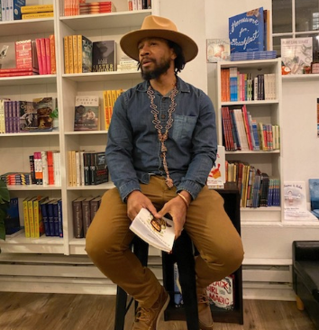 Negus Adeyemi poet with book in library